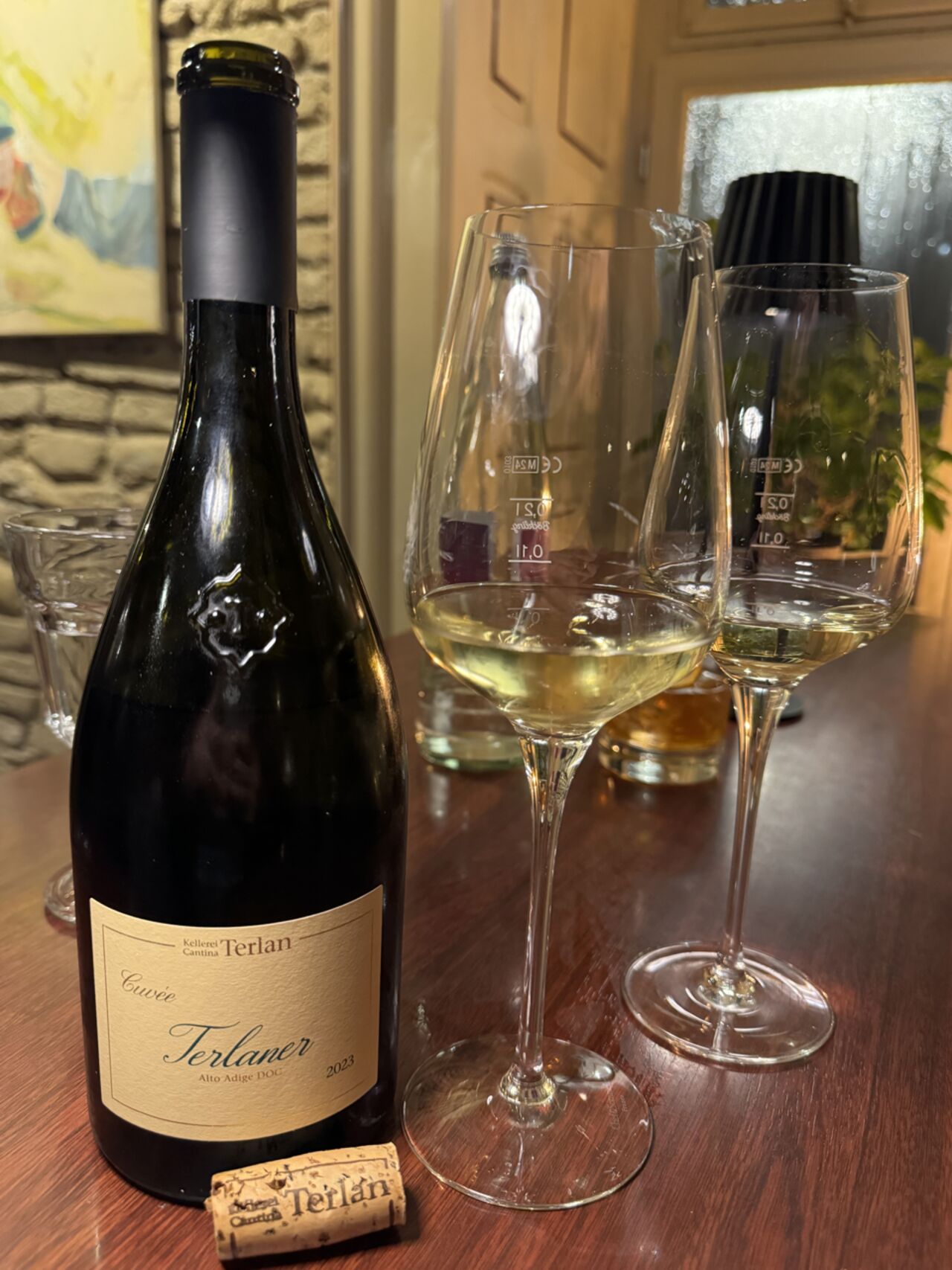 Flasche Terlaner Cuvée 2023 aus Südtirol, daneben zwei Gläser Weißwein und der Korken